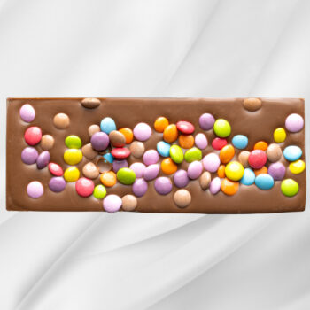 Sjokoladeplate «Barnas Favoritt» – melk- og karamellsjokolade toppet med fargerike sjokoladelinser på hvit bakgrunn