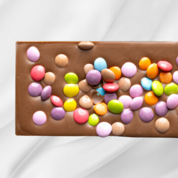 Bilde av Barnas Favoritt – sjokoladeplate med melk- og karamellsjokolade toppet med fargerike sjokoladelinser, morsomt og innbydende presentert.