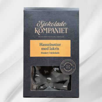 Bilde av Drasjerte Hasselnøtter – pose med bakte hasselnøtter drasjert i sjokolade og salt lakrispulver, elegant presentert som gave.