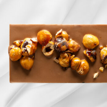 Bilde av Karamellisert Hasselnøtt – sjokoladeplate med melk- og karamellsjokolade, tilsatt hele karamelliserte hasselnøtter, elegant presentert som gave.