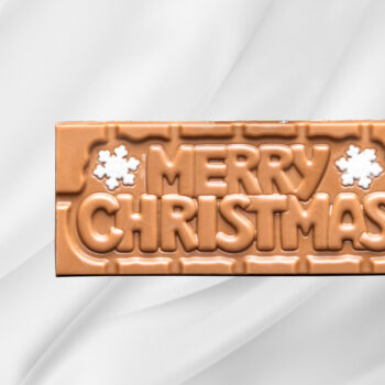 Bilde av Merry Christmas – sjokoladeplate med melk- og karamellsjokolade preget med julehilsen, en smakfull og stemningsfull gave til jul.