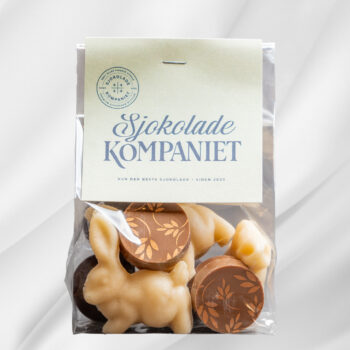 Bilde av en pose med utvalgte påskeprodukter fra Sjokoladekompaniet, fylt med sjokoladetrekte marsipanegg, sjokoladebiter og små marsipanfigurer, pakket i en gavepose til påske.